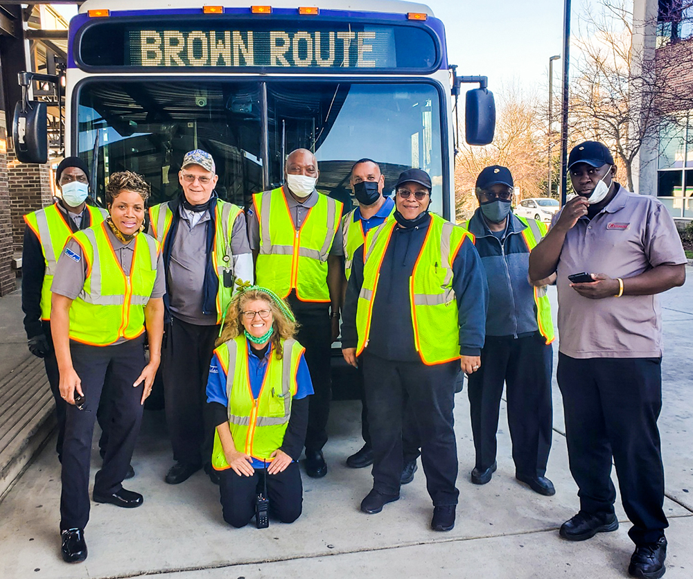 Rider transit employees in front of a bus